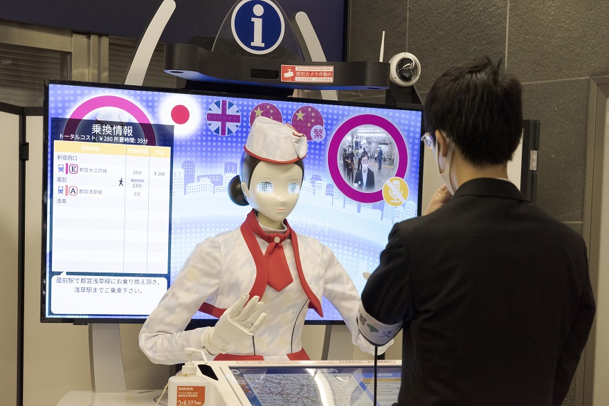 A robot concierge guiding a traveler at a Tokyo Metro booth