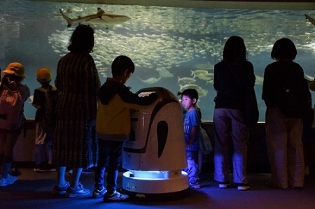 来館した子供たちに囲まれて水槽の展示説明をするペリンの写真