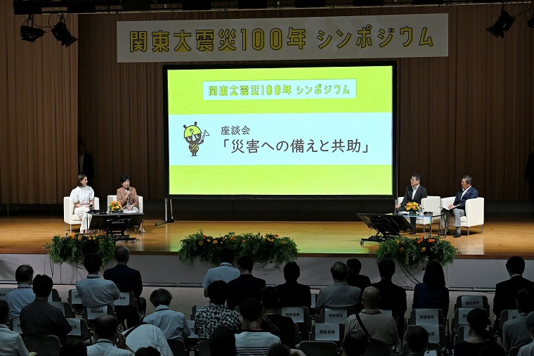 Photo: Roundtable speakers on the stage with a large screen in the background