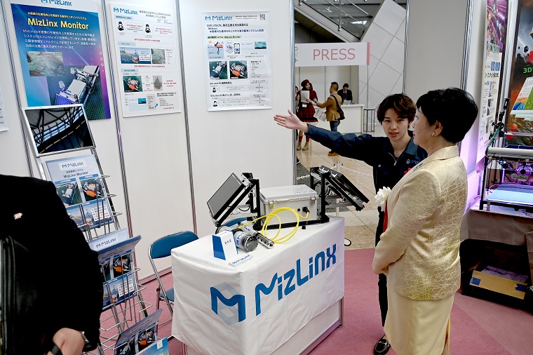 Photo: Governor Koike listening to an explanation by an award winner