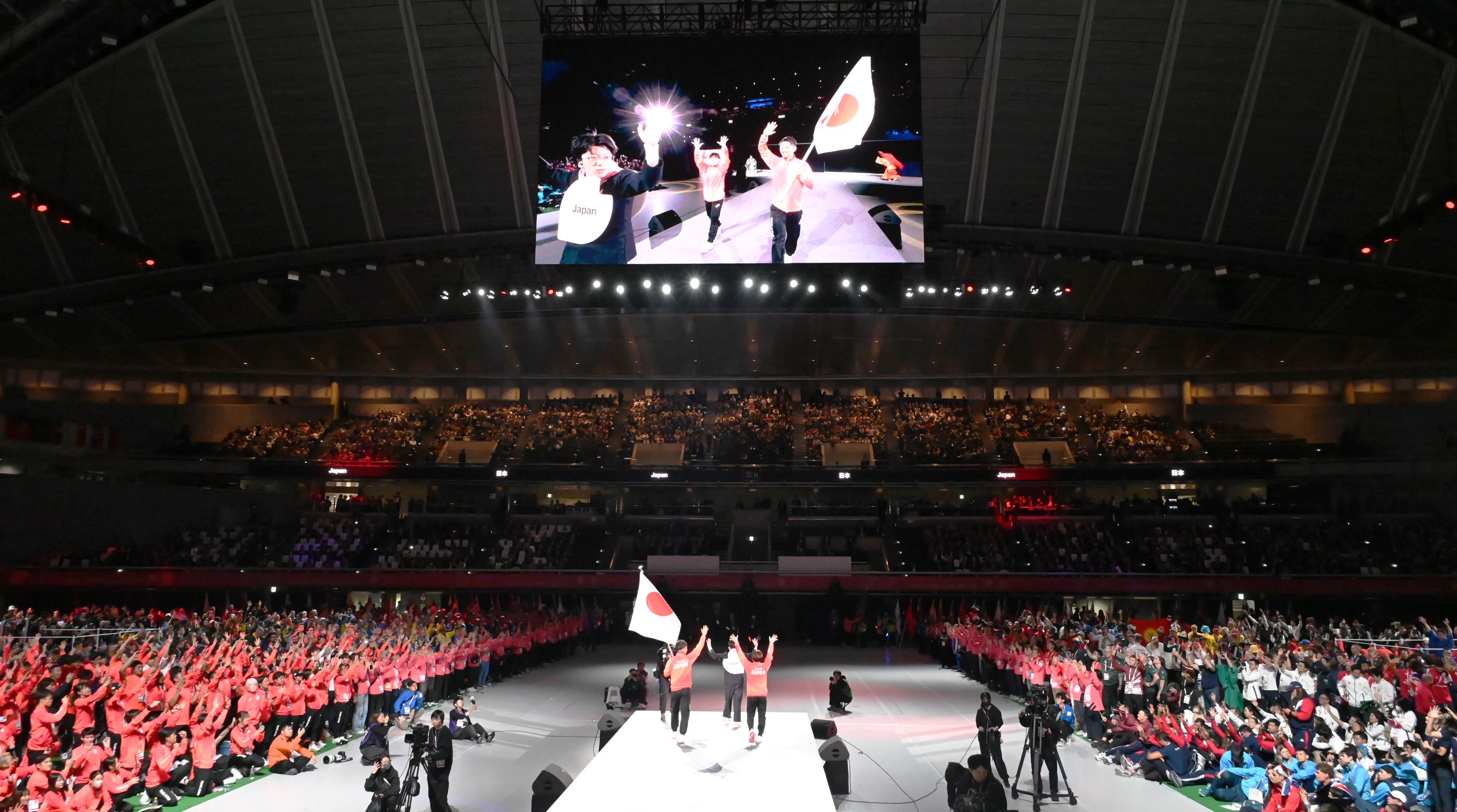 手話の拍手で迎えられる日本代表の旗手の写真